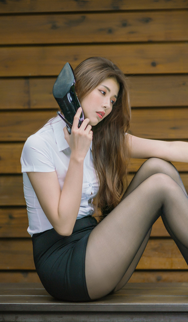 Молодая азиатка с черными туфлями в руках 