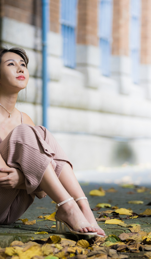 Молодая девушка азиатка сидит на земле с листьями 