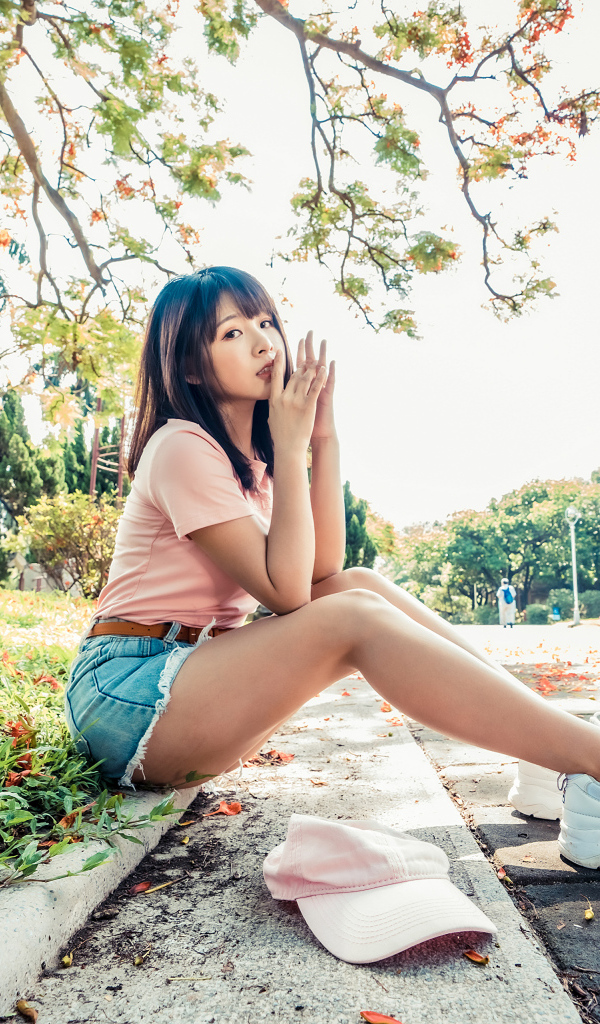 Молодая азиатка сидит на земле в осеннем парке