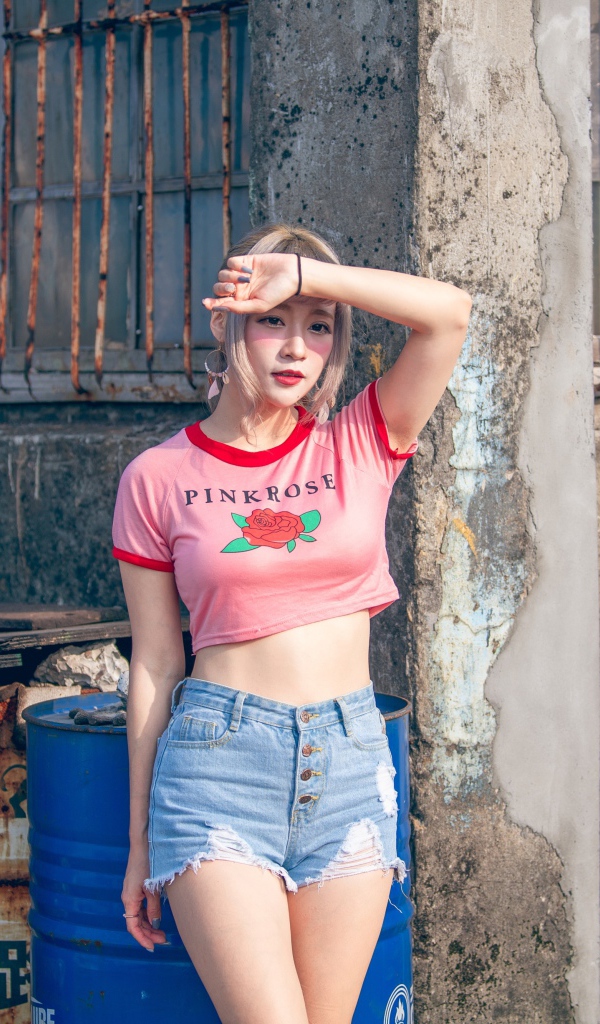 Молодая азиатка стоит у стены 