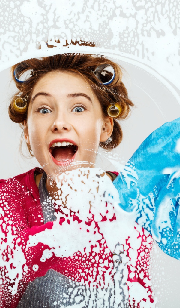 Молодая девушка в бигудях моет окно