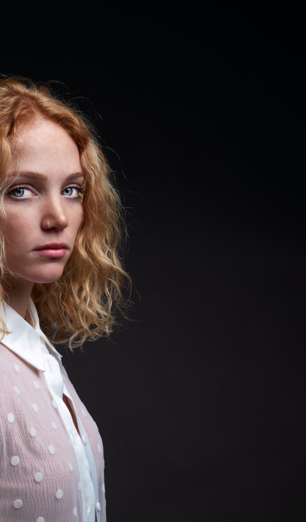 Молодая рыжеволосая девушка на черном фоне