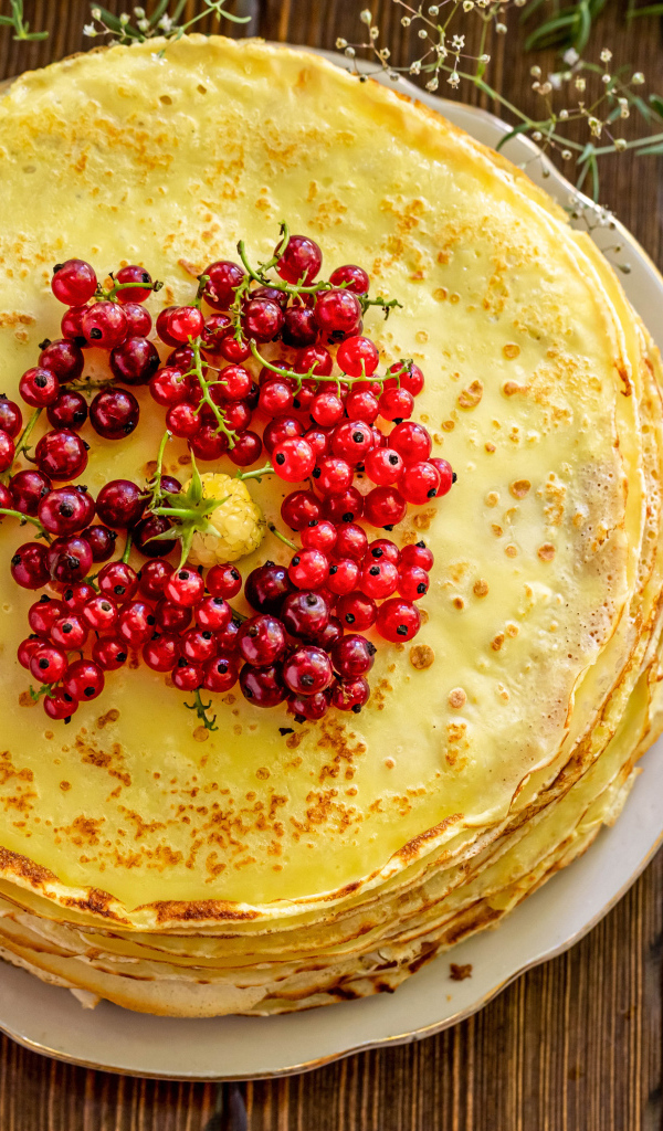 Аппетитные блины с ягодами красной смородины на столе 