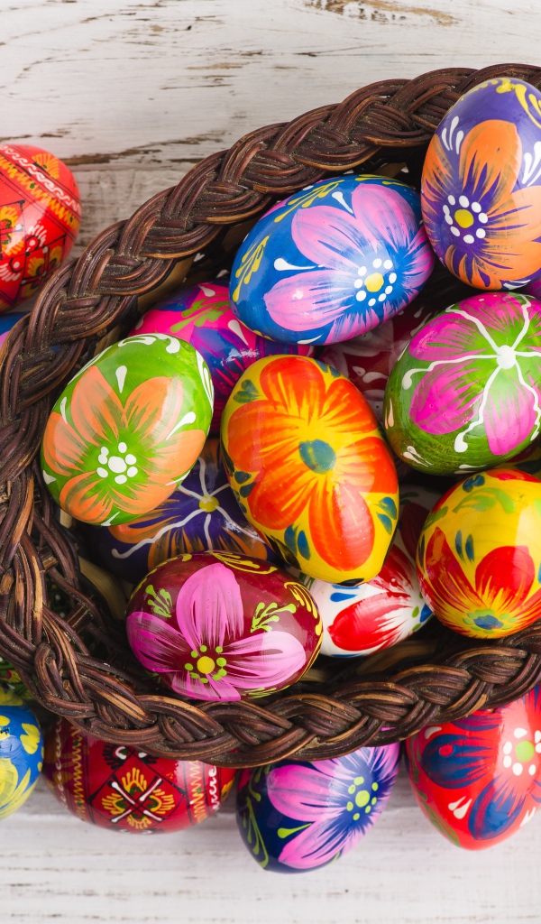 Красивые крашеные яйца в корзине на столе на праздник Великой Пасхи