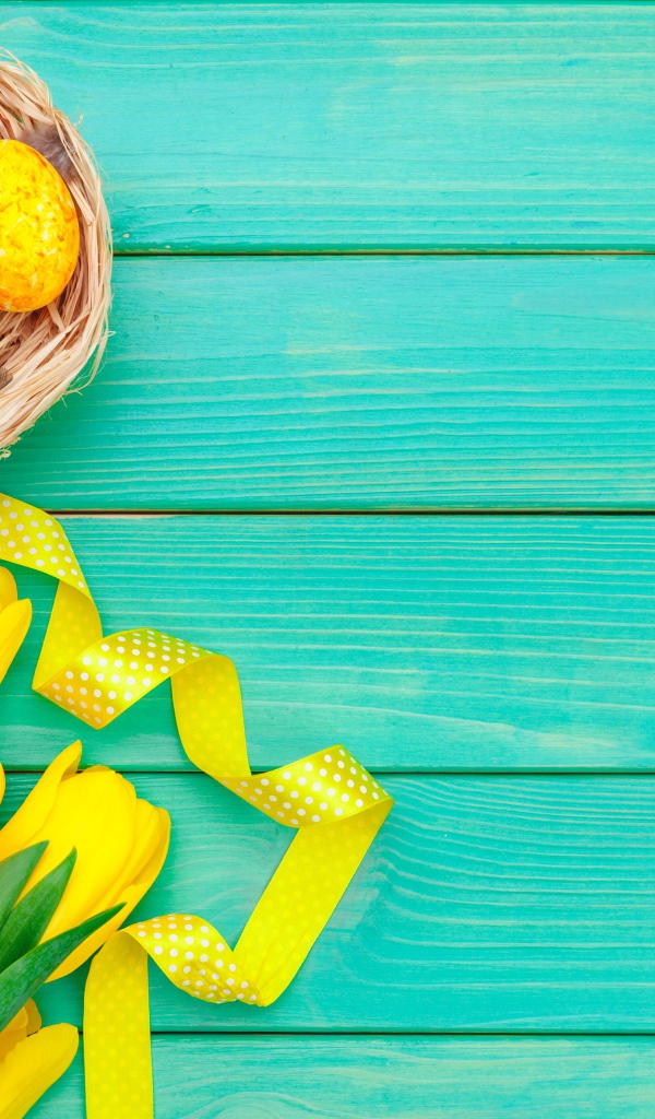 Разноцветные пасхальные яйца  и букет желтых тюльпанов на голубом фоне