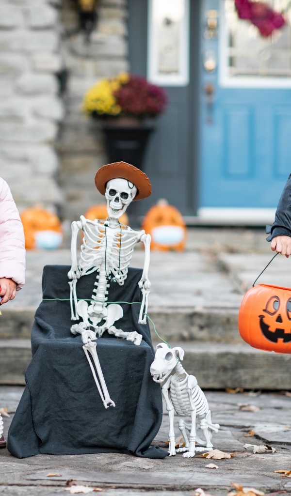 Маленькие дети со скелетом на праздник Хэллоуин