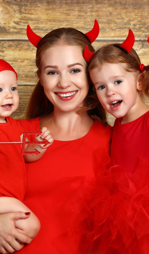 Женщина с двумя детьми в красных костюмах на Хэллоуин