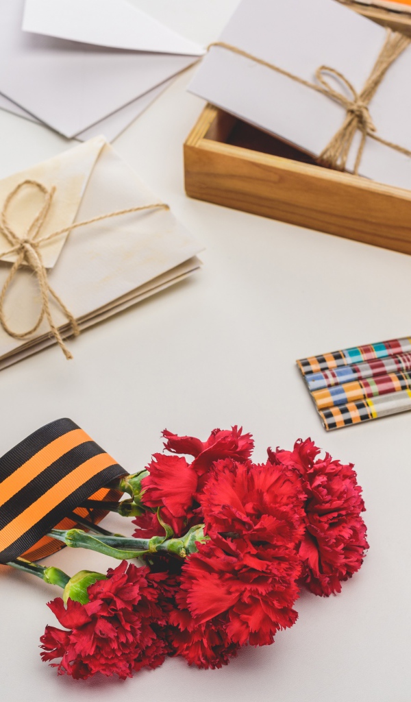 Букет красных гвоздик, ордена и часы на День победы 9 мая