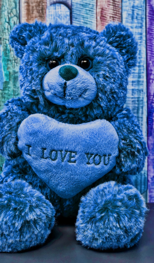 Синий медведь с сердцем на фоне забора