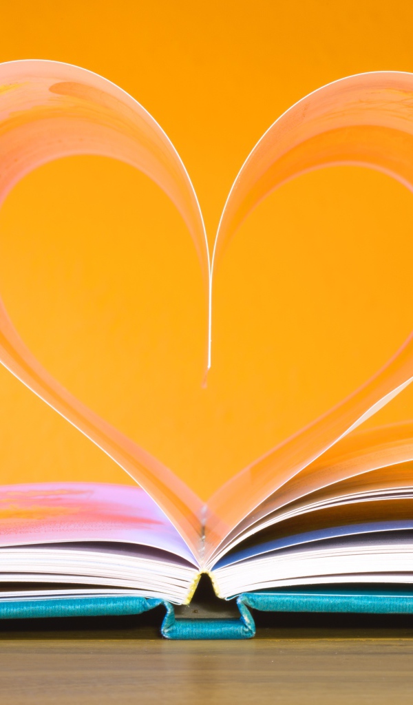 Сердце из страниц книги на оранжевом  фоне  