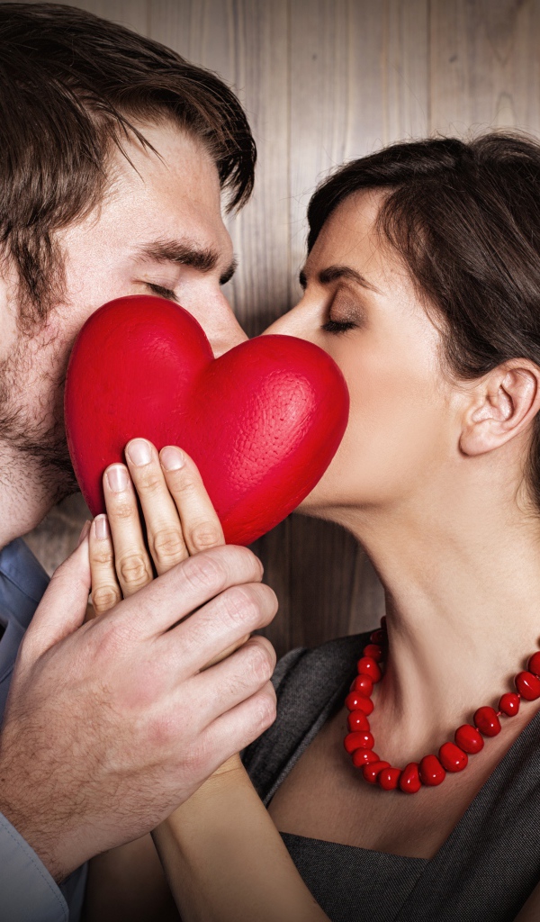 Поцелуй влюбленной пары за красным сердцем