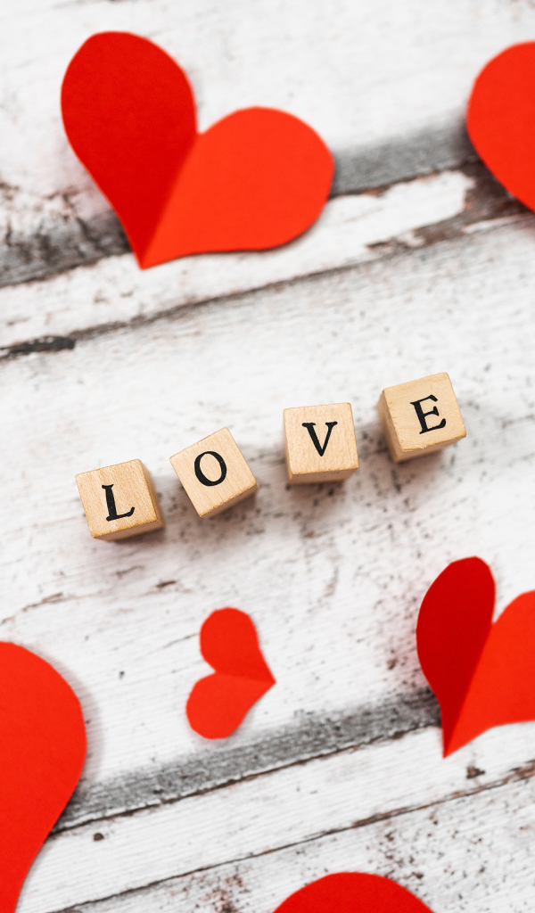 Красные сердечки и надпись любовь на деревянном столе 