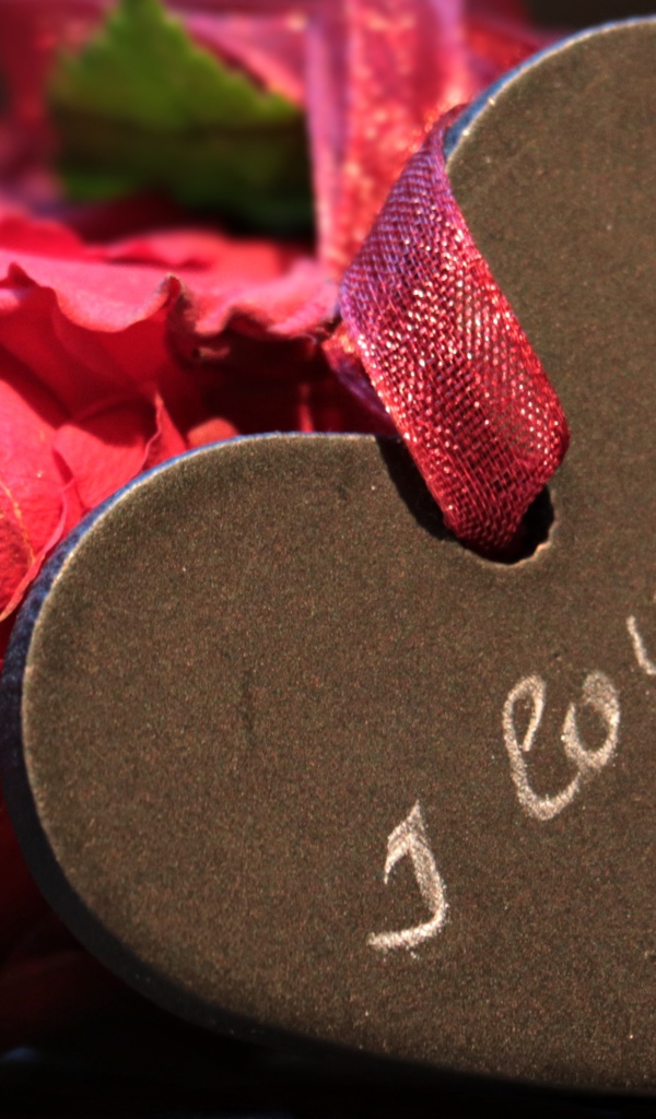 Каменное сердце с ленточкой на столе с розой 