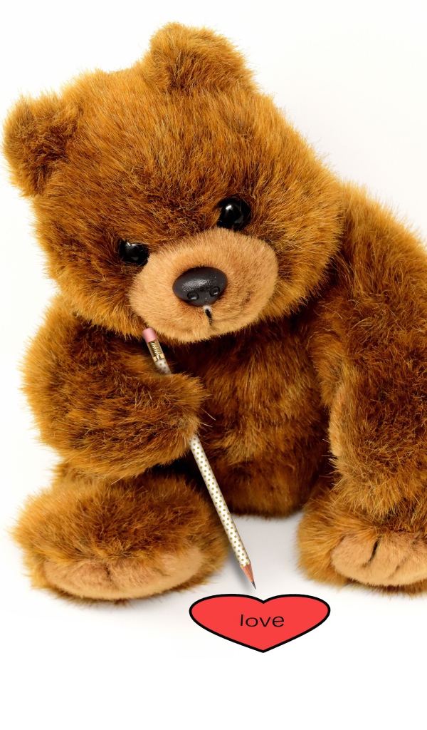 Игрушка медвежонок рисует сердце на белом фоне 