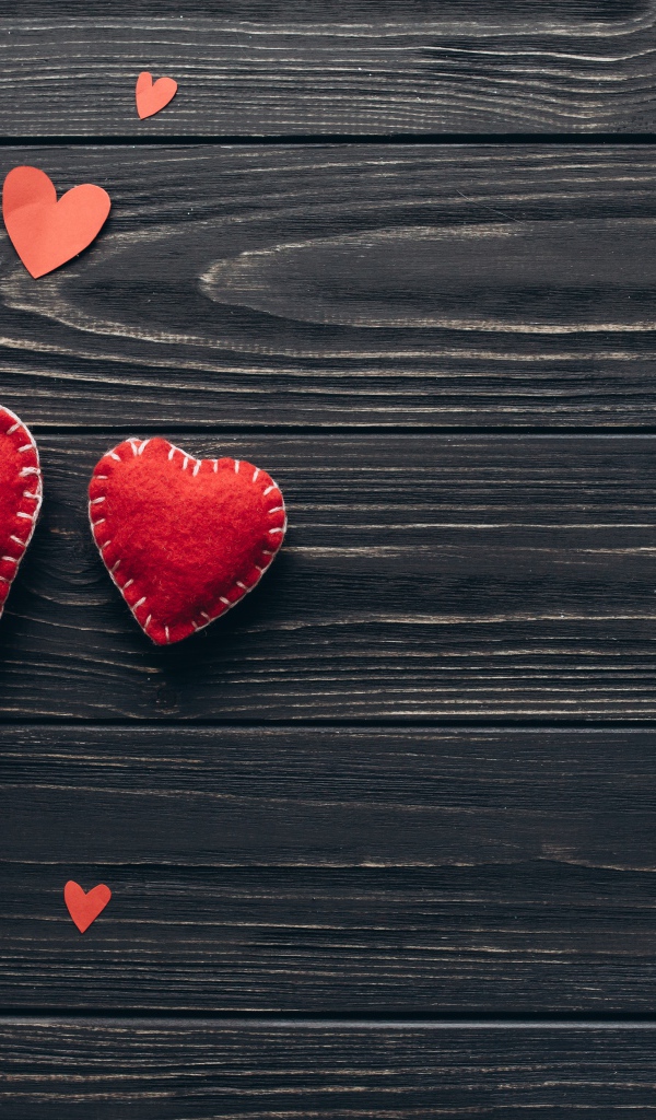 Два больших  красных сердца с маленькими  на деревянном столе 