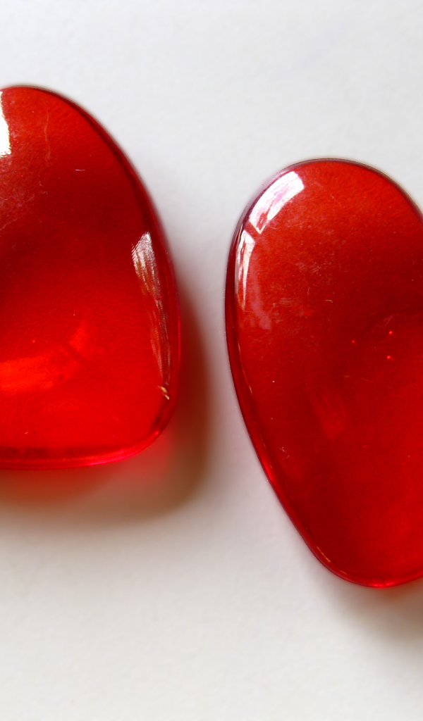 Два красных стеклянных сердца на сером фоне