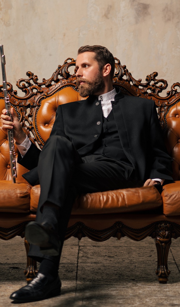 Солидный мужчина в костюме сидит на диване