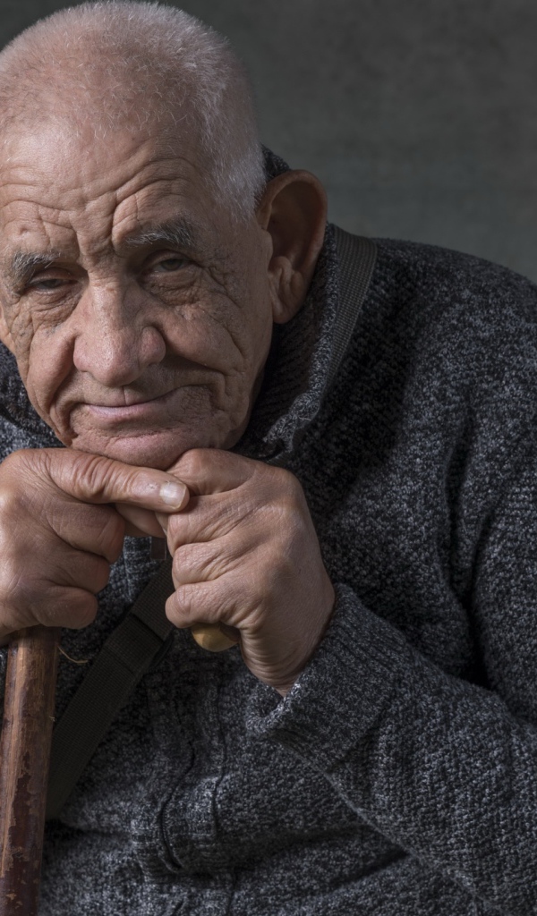 Elderly man in warm sweater on gray background