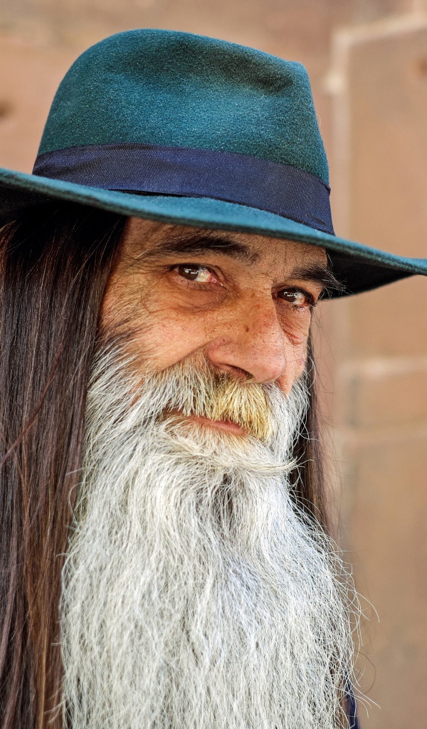 Пожилой мужчина с длинными волосами в шляпе 