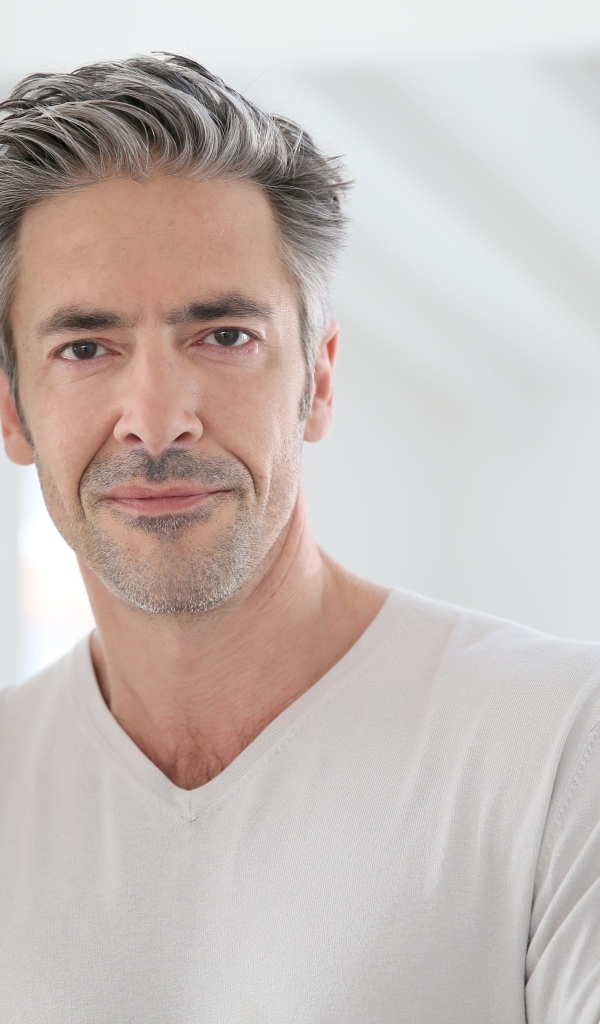 Седой стильный мужчина у стены