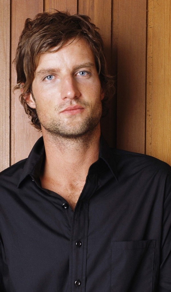 Красивый мужчина в черной рубашке на деревянном фоне