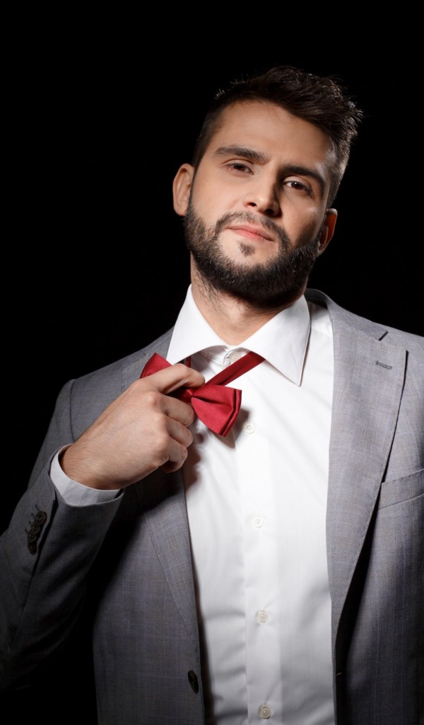 Красивый мужчина в сером пиджаке на черном фоне