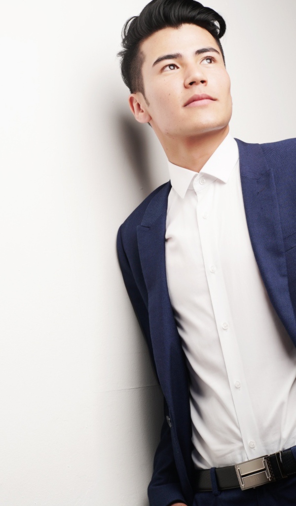 Мужчина модель в костюме у белой стены