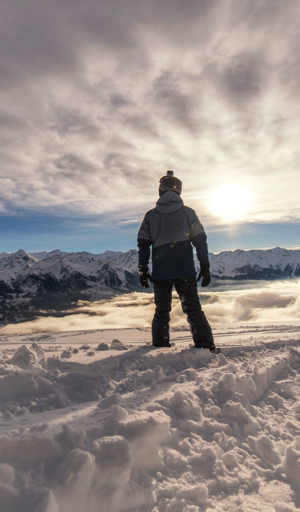 Человек в заснеженных горах в лучах солнца