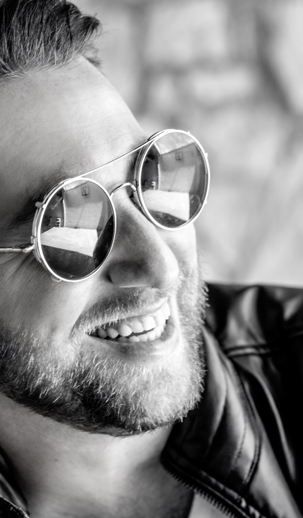 Улыбающийся брутальный мужчина в черных очках