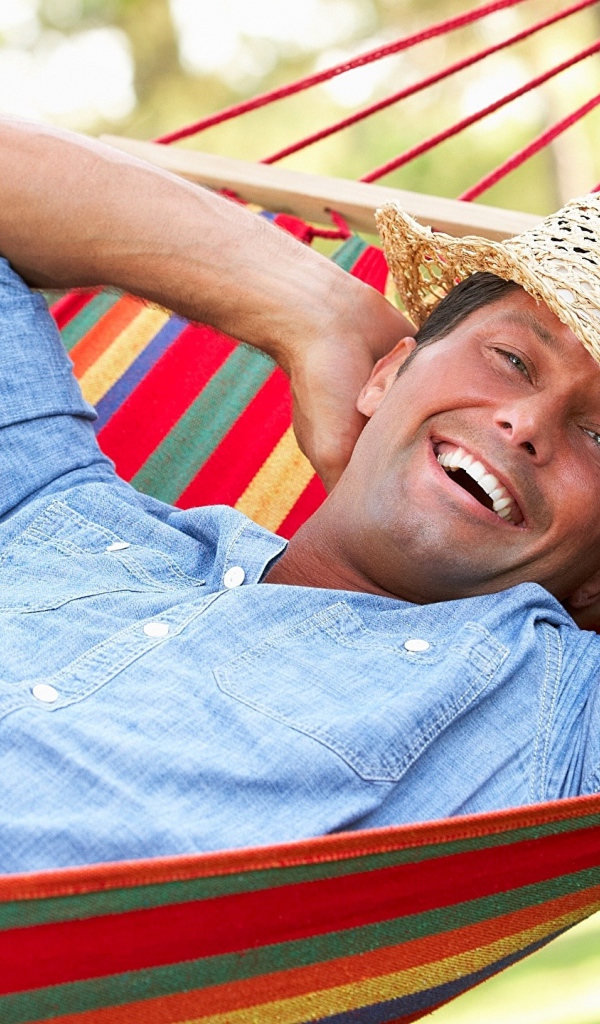 Улыбающийся мужчина спит в гамаке