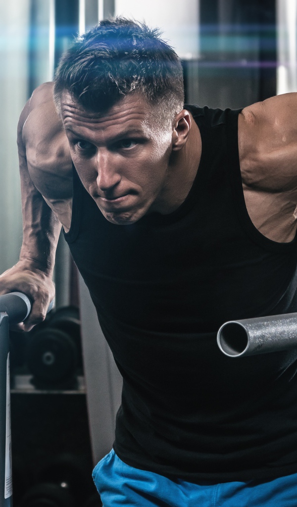 Сильный накаченный мужчина занимается в спортзале 