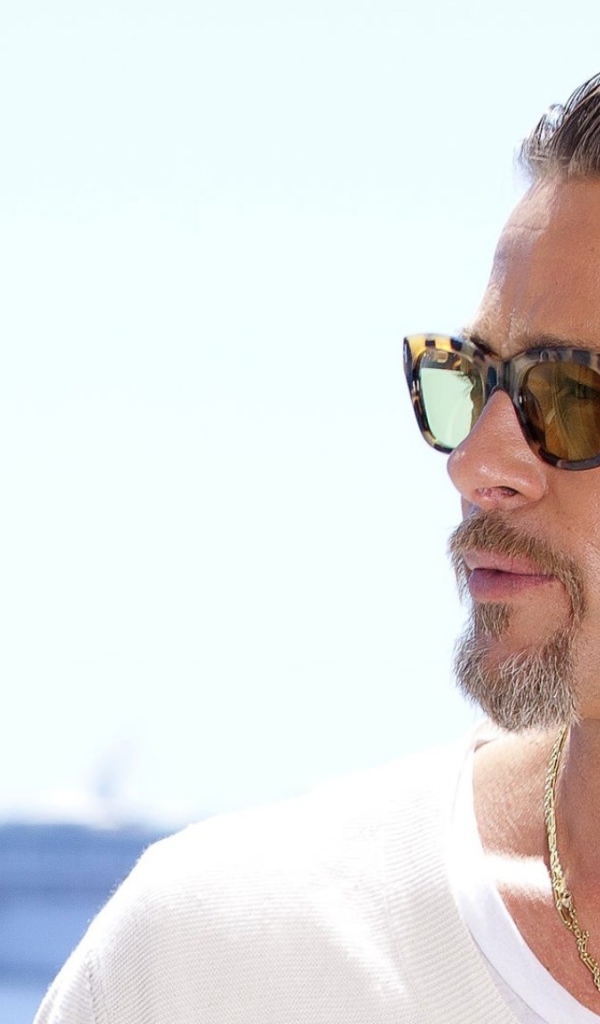 Актер Брэд Питт в очках на фоне океана