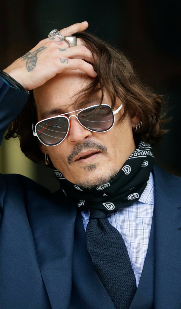 Актер Джонни Депп в очках с татуировками на руке