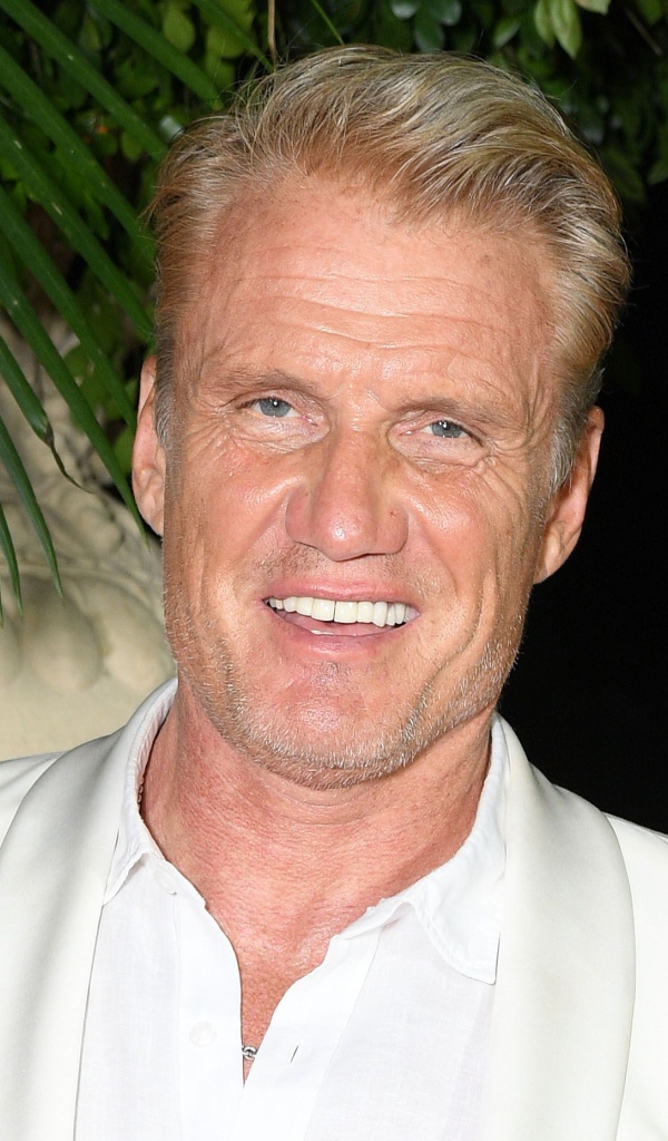 Улыбающийся актер Дольф Лундгрен в белом костюме