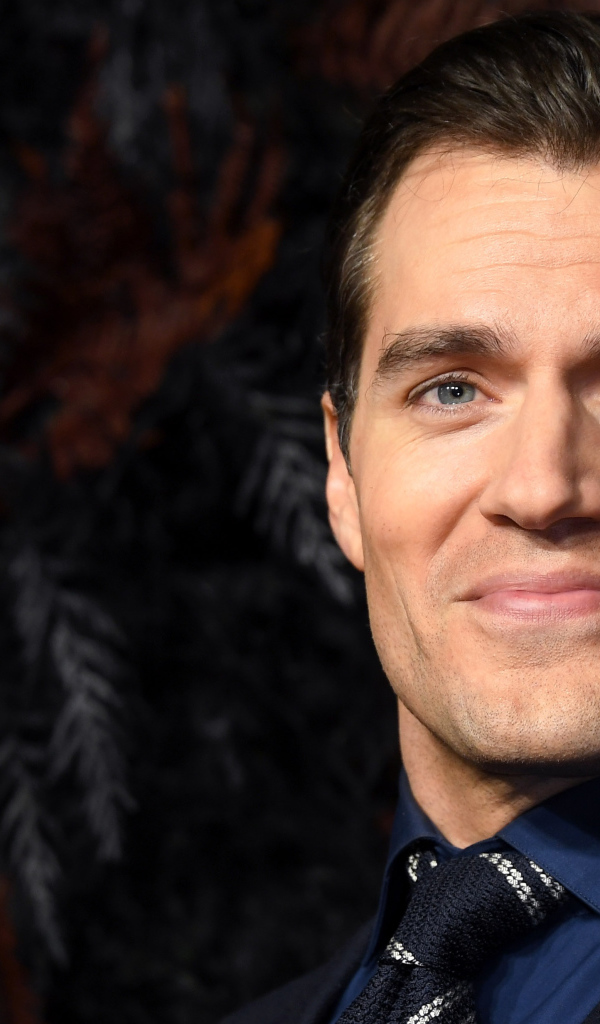 Улыбающийся актер Генри Кавилл в костюме