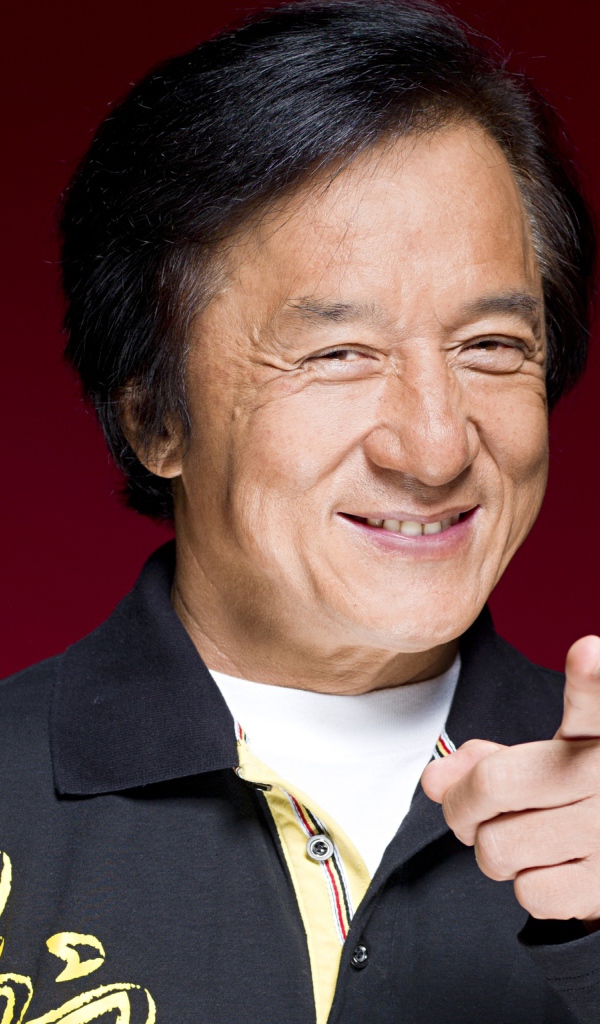 Улыбающийся мужчина, актер Джеки Чан на красном фоне