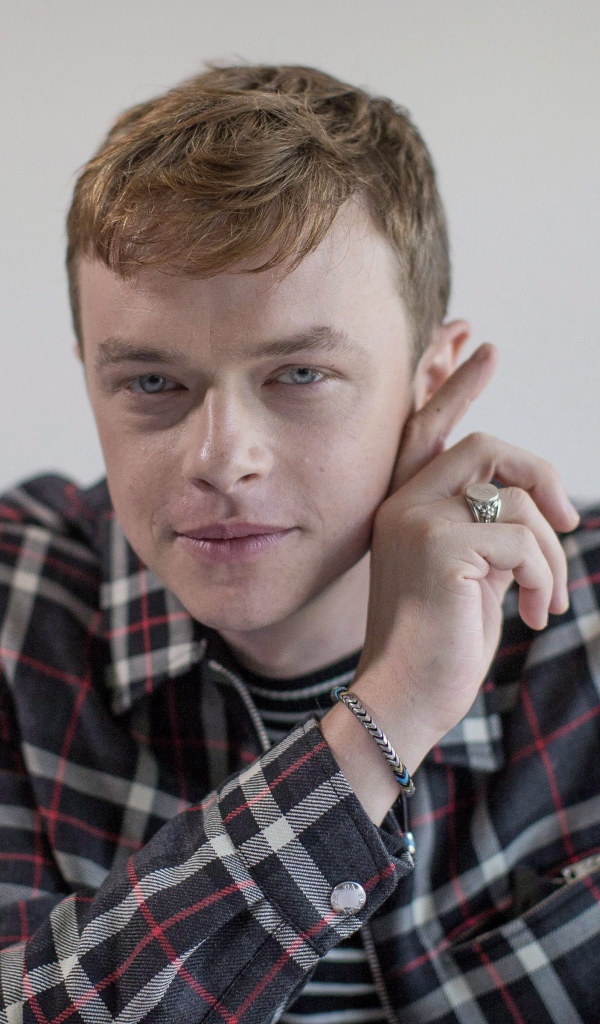 Молодой актер Дэйн Дехаан в рубашке на сером фоне