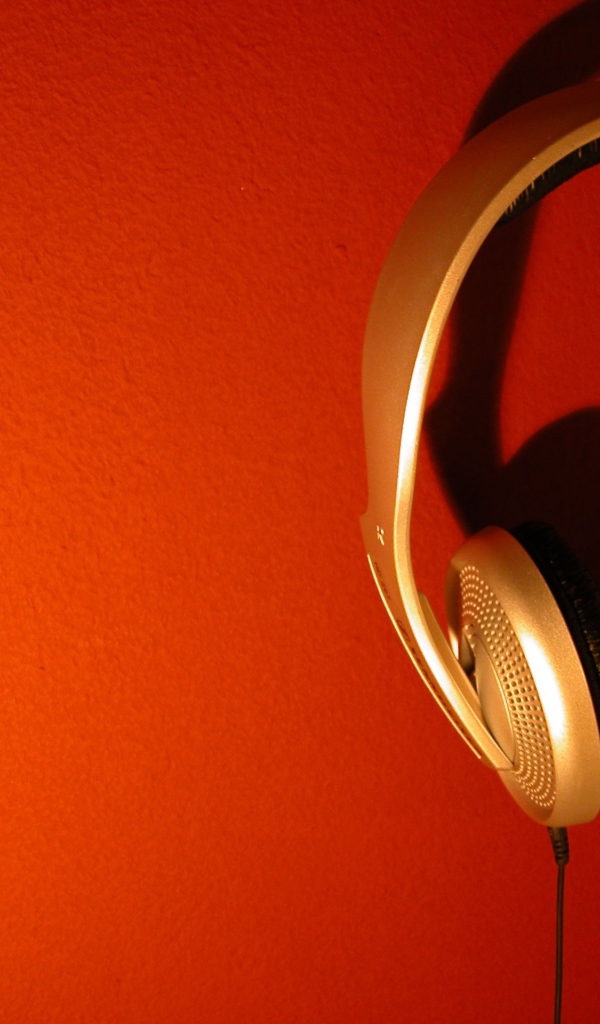 Большие золотые наушники на оранжевом фоне 