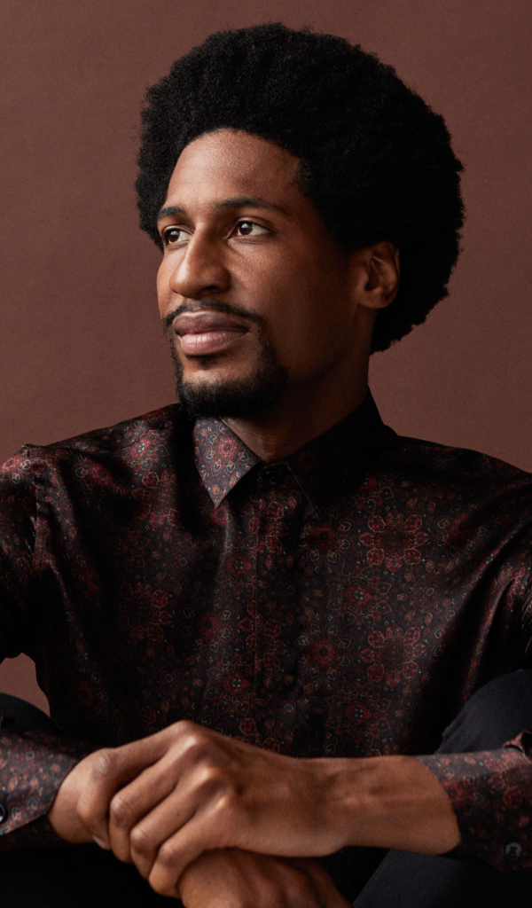 Музыкант Джонатан Батисте на коричневом фоне