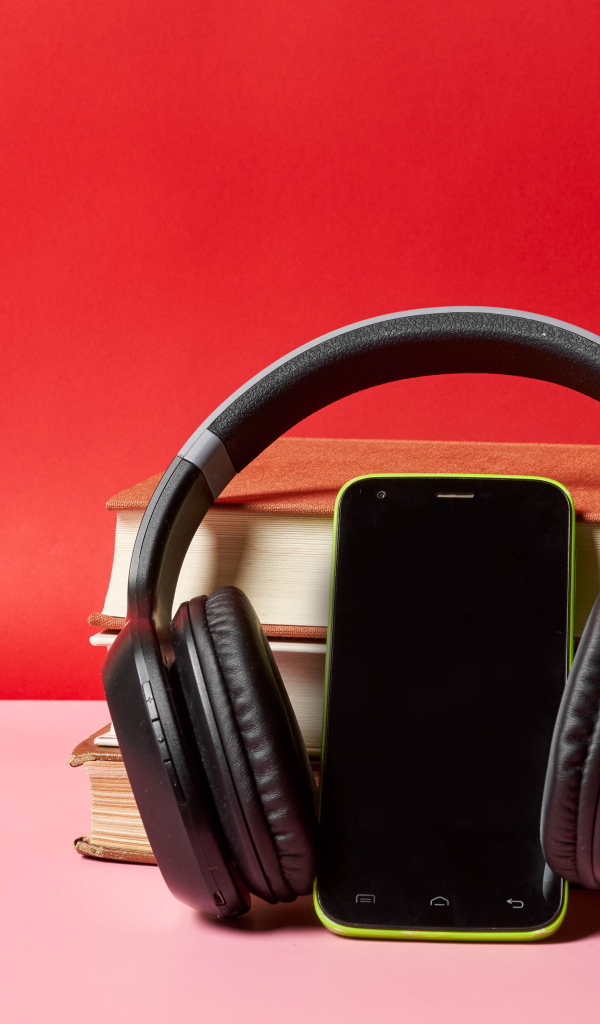 Смартфон, наушники и книги на красном фоне
