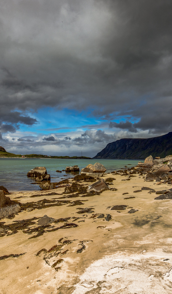 Большие камни на берегу фьорда под грозовым небом 