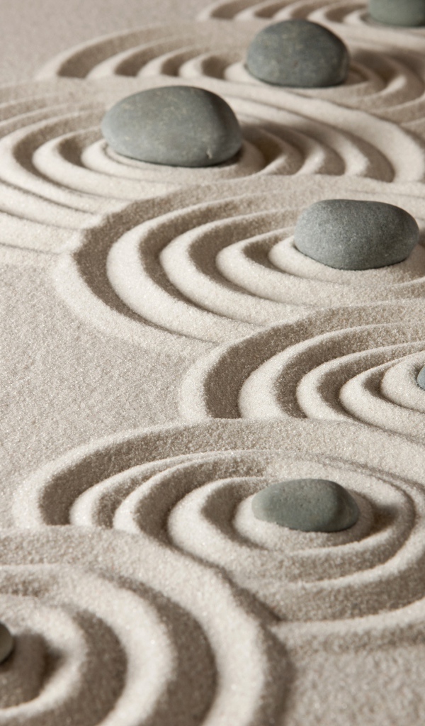 Маленькие серые камни с кругами на песке 