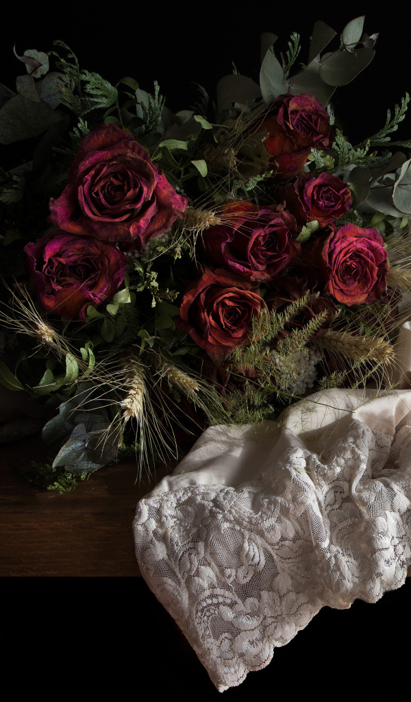 Завядший букет роз со свечой на столе