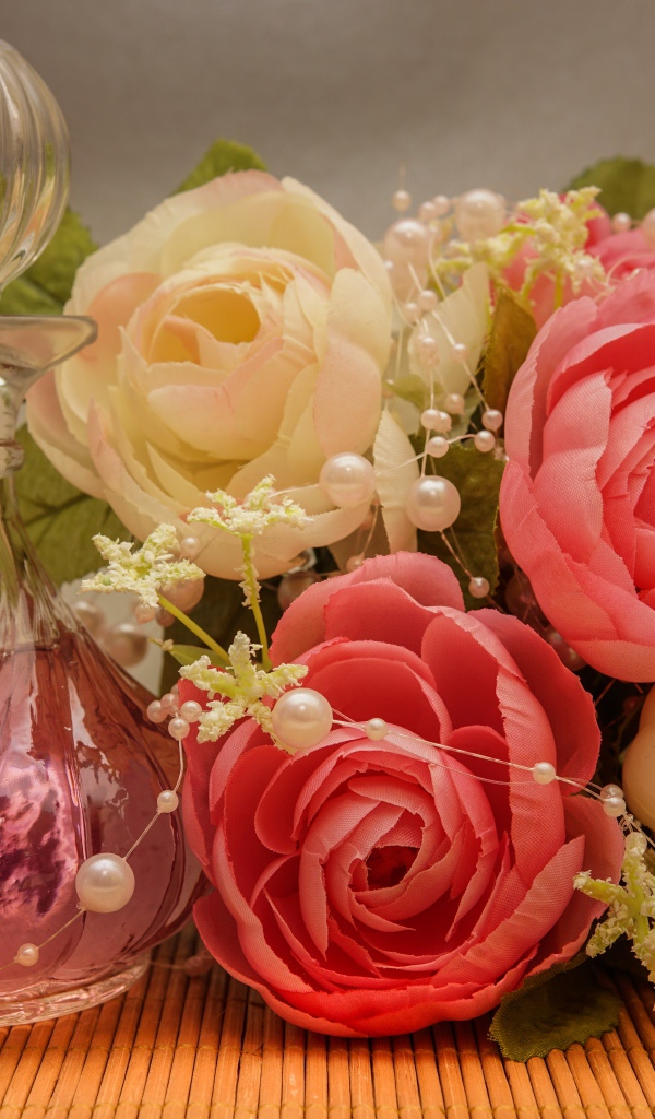 Красивый букет искусственных роз на столе с духами