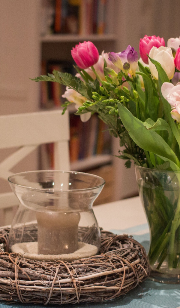 Красивый букет ярких цветов на столе со свечой