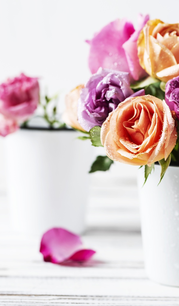 Букет разноцветных роз в белой вазе на столе