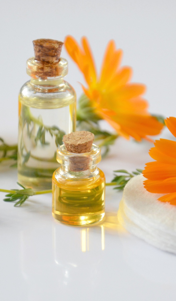 Оранжевые цветы календулы с маслом на столе