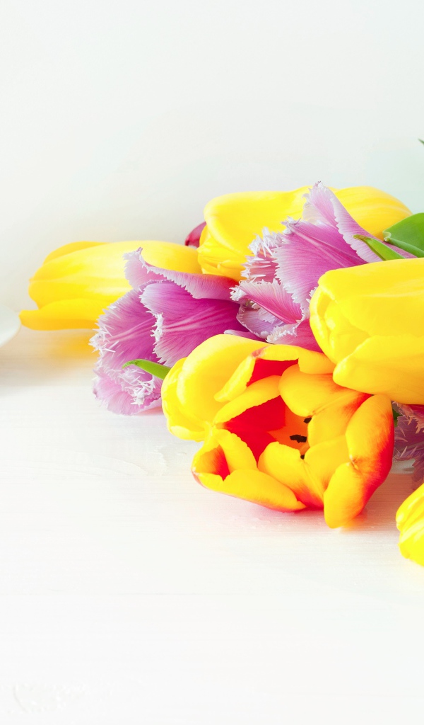 Желтые и розовые тюльпаны на столе с кофе