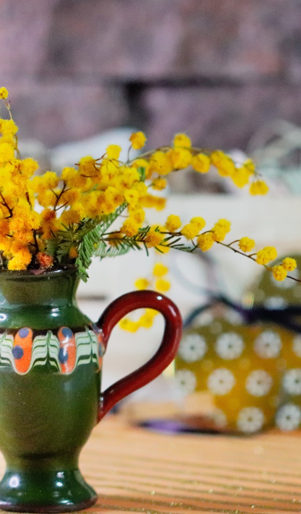 Желтые цветы мимозы в маленькой вазе на столе