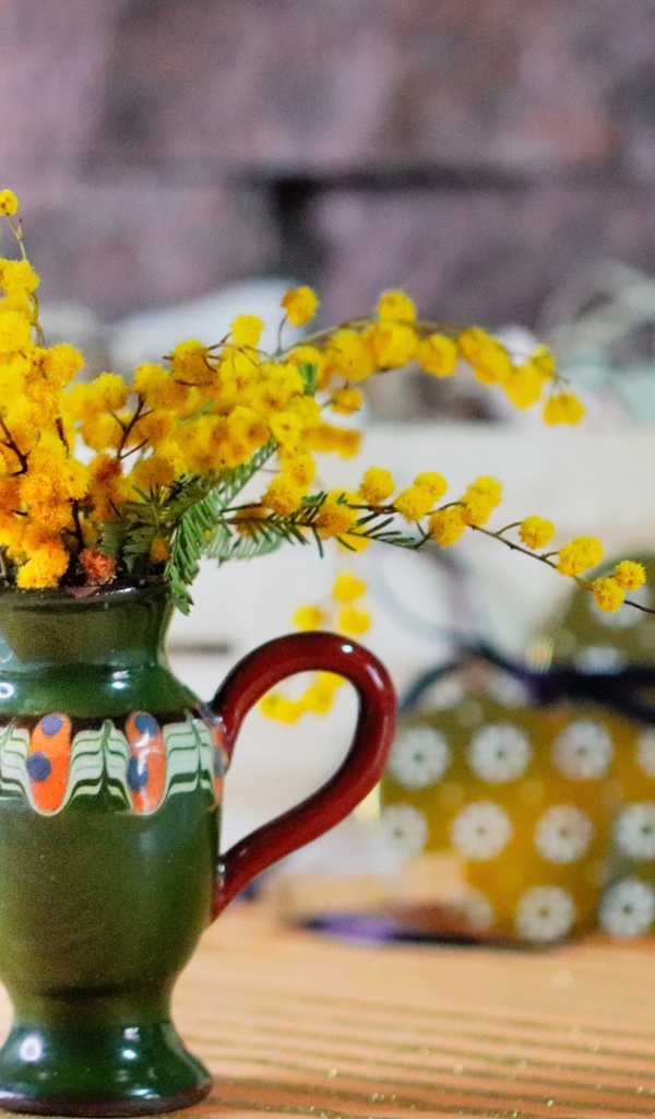 Желтые цветы мимозы в маленькой вазе на столе